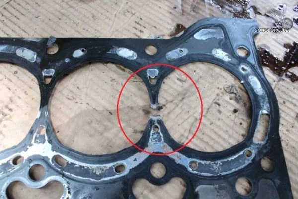 The cylinder head gasket between the engine blocks is cracked and damaged.